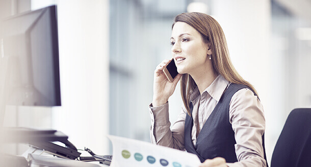 A woman looking at a screen and talking on a mobile phone